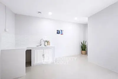 Minimalist kitchen with white cabinetry and sleek tile backsplash in modern apartment.