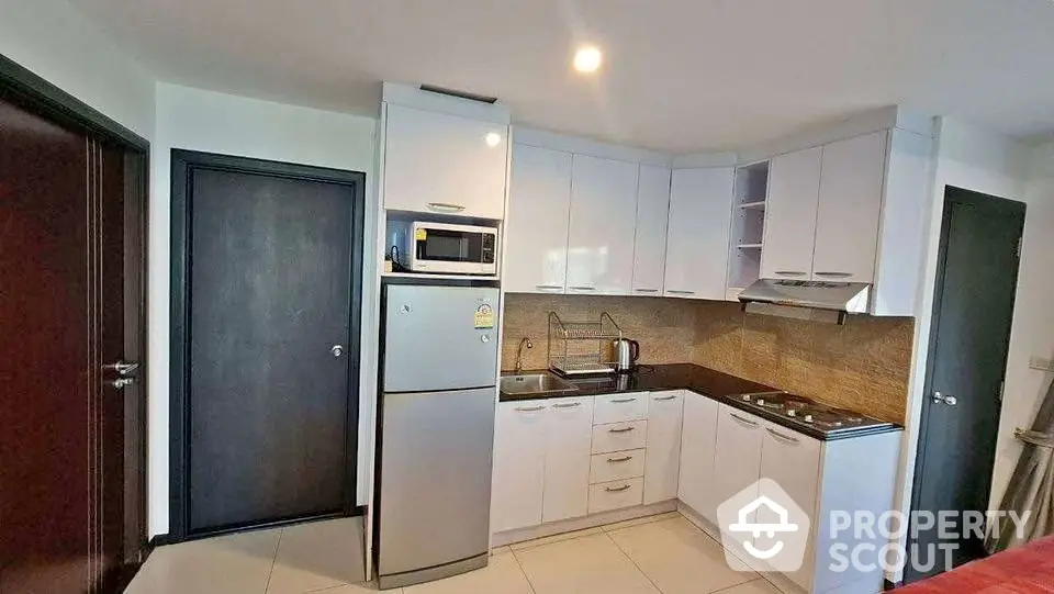 Modern kitchen with sleek white cabinets, stainless steel appliances, and a compact layout for efficient cooking.