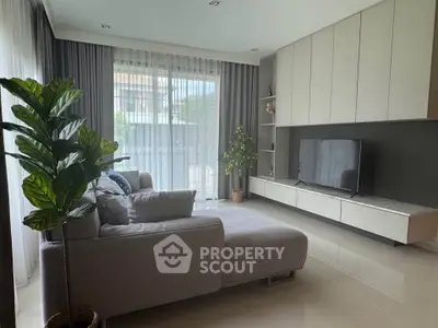 Modern living room with large windows, stylish furniture, and natural light.