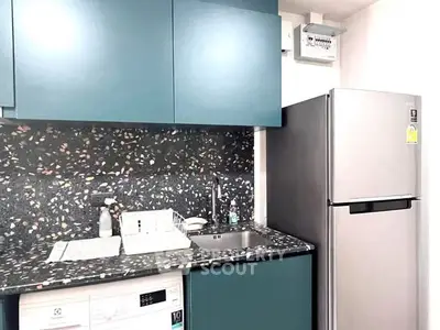 Modern kitchen with sleek cabinets, terrazzo backsplash, and stainless steel fridge.
