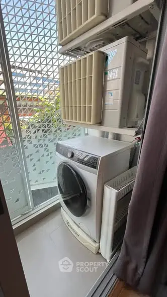 Compact balcony with washing machine and air conditioning units in modern apartment.