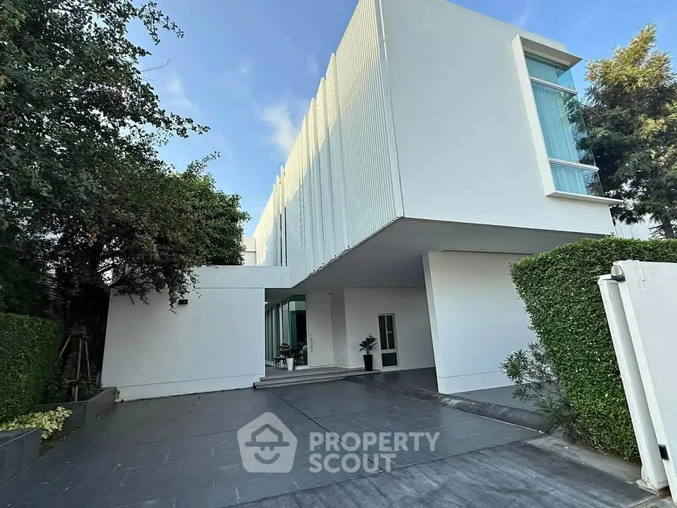 Modern minimalist white building with sleek design and lush greenery