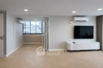Spacious modern living room with air conditioning and large TV, featuring elegant wood flooring.