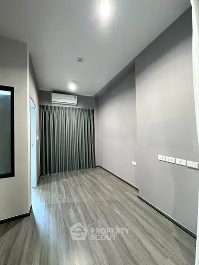 Spacious empty room with modern flooring and air conditioning, ready for customization.