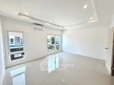 Spacious unfurnished living room with large windows and modern lighting in a bright home.