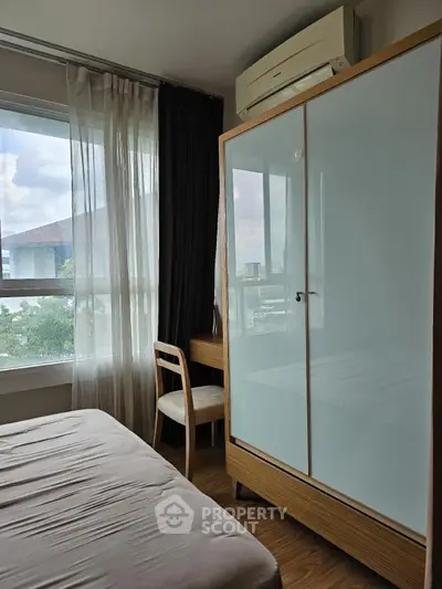 Cozy bedroom with large window and modern wardrobe in urban apartment