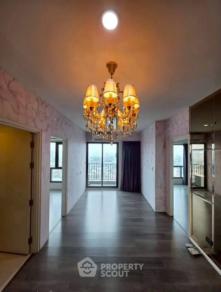 Elegant living room with chandelier and balcony view, featuring modern design and spacious layout.