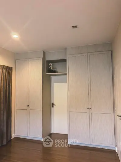 Spacious bedroom with elegant built-in wardrobes and wooden flooring