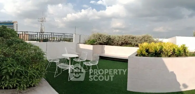 Stunning rooftop garden with modern seating and lush greenery under a cloudy sky.