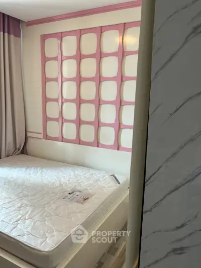 Charming bedroom with unique pink accent wall and cozy mattress, perfect for a restful retreat.