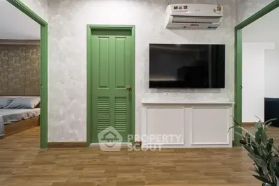 Modern living room with green doors, wall-mounted TV, and wooden flooring