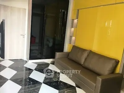 Modern living room with stylish yellow accent wall and sleek black and white flooring.