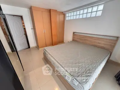 Spacious bedroom with modern wooden wardrobe and large bed in a well-lit apartment.