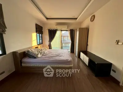 Spacious bedroom with wooden flooring and large windows for natural light