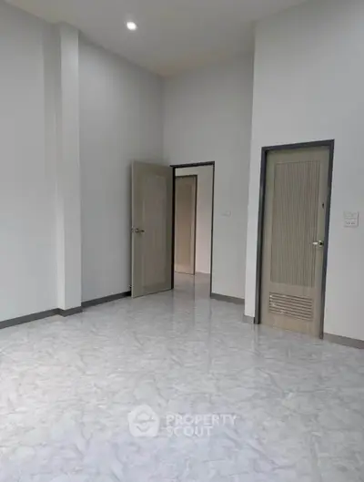 Spacious empty room with marble flooring and open doors in modern apartment.