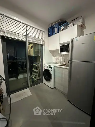 Modern kitchen with washing machine and fridge, featuring a balcony view.