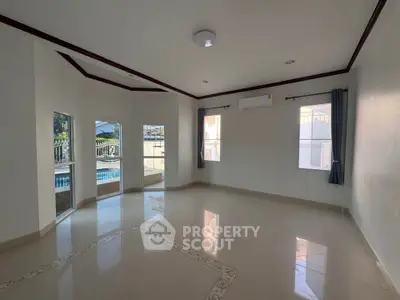 Spacious living room with large windows and pool view, perfect for natural light and relaxation.