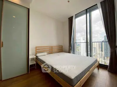 Modern bedroom with city view and large windows in high-rise apartment.
