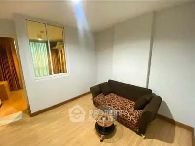 Cozy living room with modern sofa and glass coffee table in a well-lit apartment.