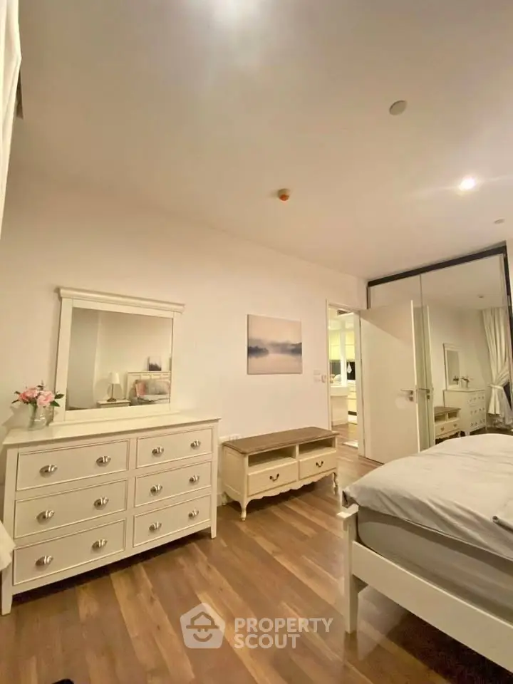 Spacious bedroom with elegant white furniture and wooden flooring