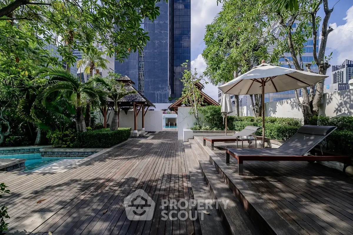 Luxurious urban garden with pool and lounge chairs in a serene setting.
