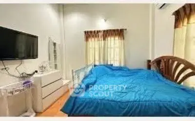 Cozy bedroom with blue bedding and wall-mounted TV, perfect for relaxation.