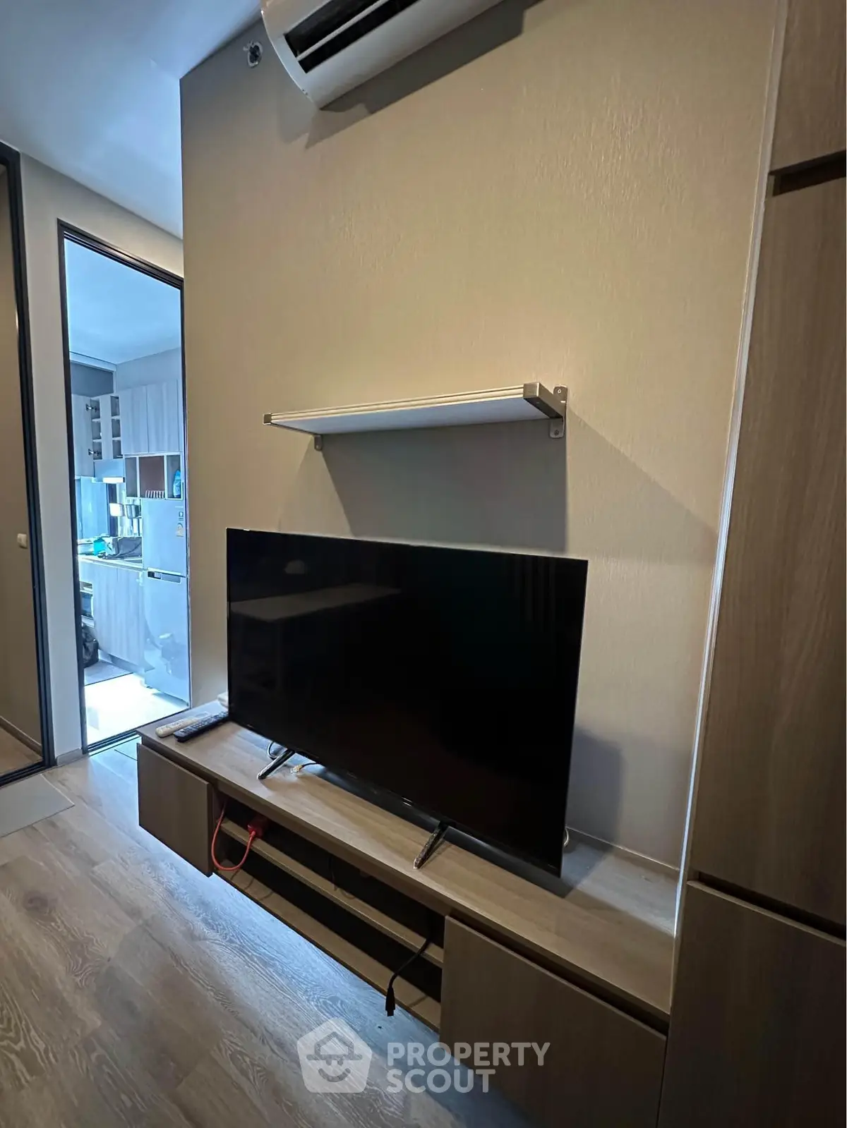 Modern living room with sleek TV setup and stylish wooden furniture, perfect for cozy entertainment.