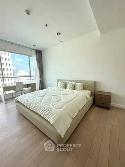 Spacious bedroom with modern decor and large window offering city view