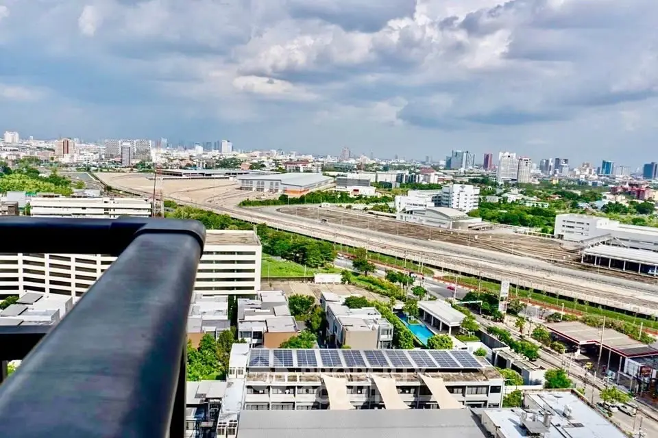 Stunning cityscape view from a high-rise balcony showcasing urban skyline and lush greenery.