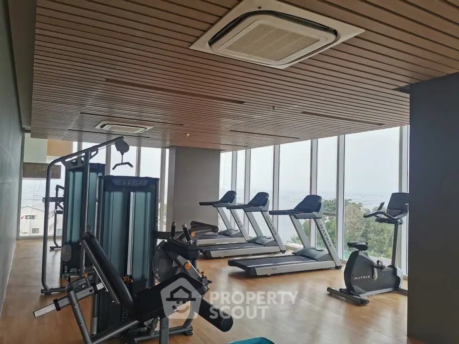 Modern gym with panoramic windows and state-of-the-art equipment in luxury building.