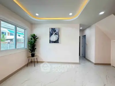 Modern living room with elegant lighting and stylish decor, featuring a large window and sleek flooring.