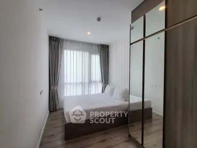Modern bedroom with large window and mirrored wardrobe in stylish apartment