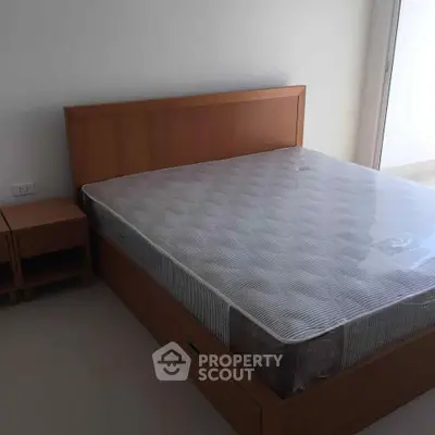 Spacious bedroom with wooden bed frame and side table, perfect for a cozy retreat.