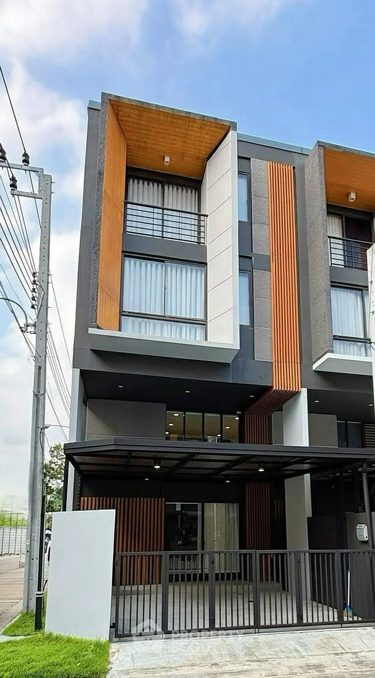 Modern three-story townhouse with unique facade design and gated entrance.