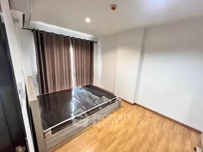 Spacious bedroom with wooden flooring and large window for natural light