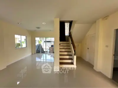 Spacious open-plan living area with staircase and large windows