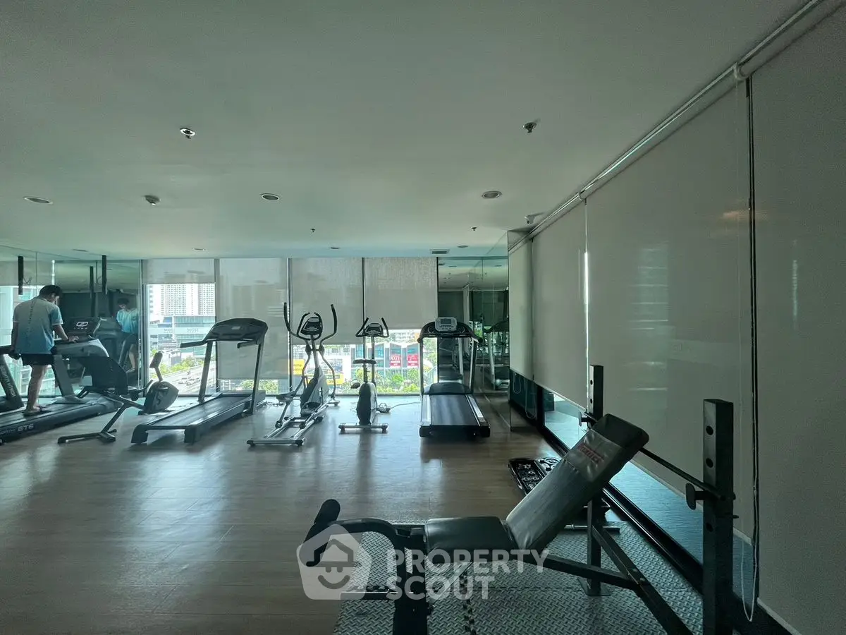Spacious gym with modern equipment and city view, perfect for fitness enthusiasts.