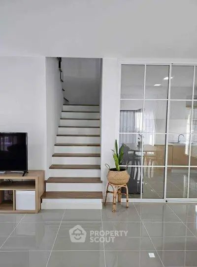 Modern interior with sleek staircase and glass sliding doors leading to kitchen