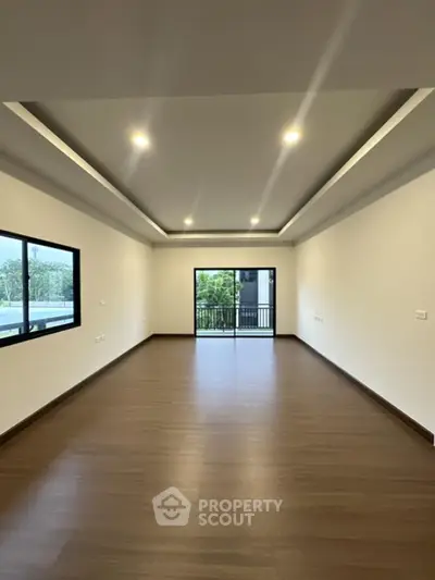 Spacious modern living room with wooden flooring and large windows.