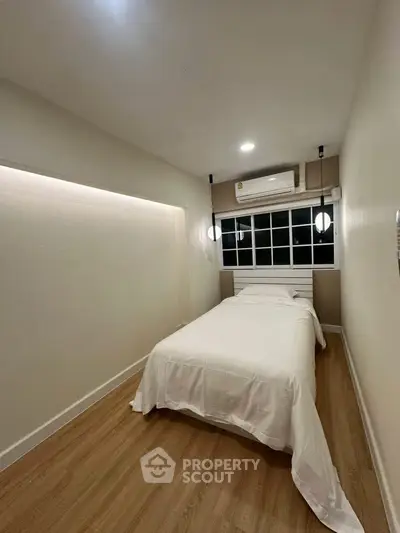 Cozy minimalist bedroom with wooden flooring and modern lighting