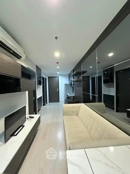 Modern living room with sleek design and neutral tones, featuring a comfortable sofa and wall-mounted TV.