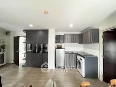Modern kitchen with sleek cabinetry, washing machine, and fridge in stylish apartment.