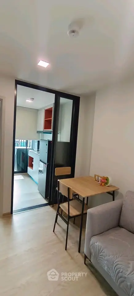 Modern apartment interior with cozy living area and open kitchen layout, featuring sleek furniture and bright lighting.