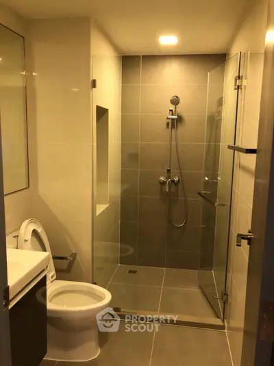 Modern bathroom with glass shower and sleek fixtures in contemporary apartment.