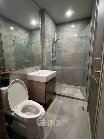 Modern bathroom with glass shower and sleek fixtures in contemporary apartment.