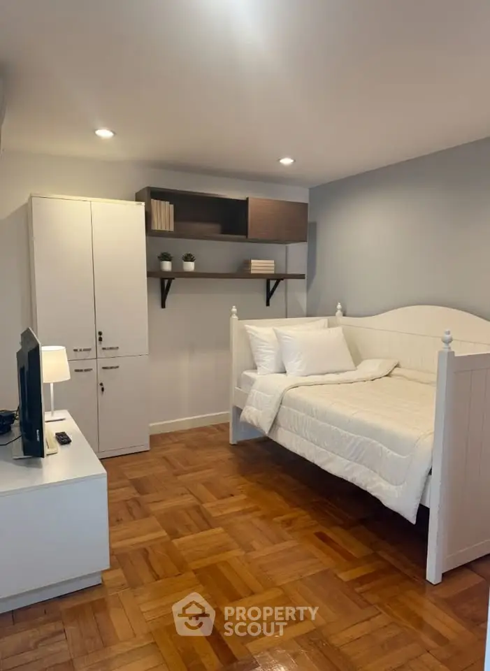 Cozy bedroom with wooden flooring, white furniture, and soft lighting for a serene ambiance.
