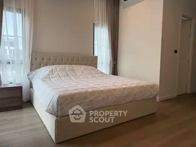 Spacious bedroom with elegant decor and large windows for natural light.