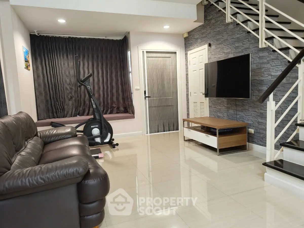 Modern living room with leather sofa, exercise bike, and wall-mounted TV in stylish home.