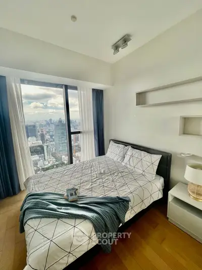 Modern bedroom with stunning city view from high-rise apartment window.