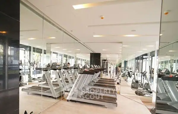 Modern gym with multiple treadmills and mirrored walls in luxury apartment complex.